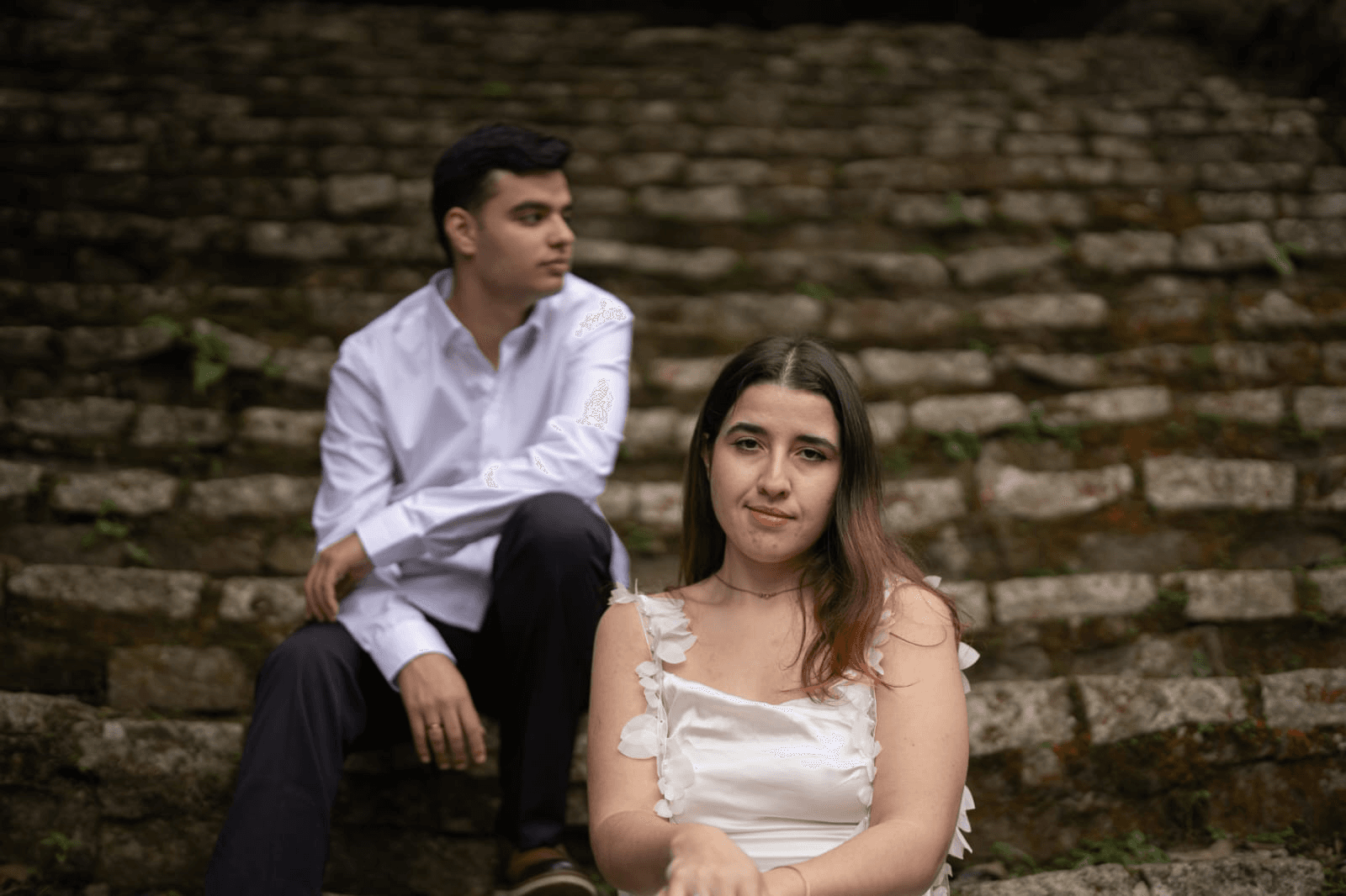Bruna e Vinícius sentados em uma escadaria de pedra